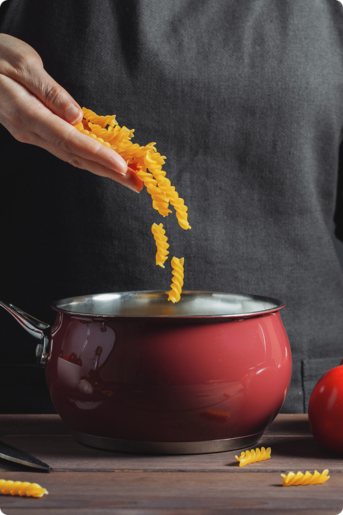 Adding pasta to red cooking pot